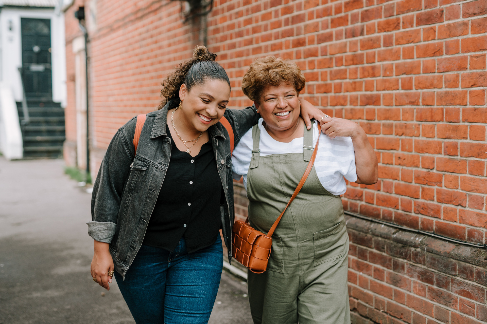 Two friends walking together along a brick wall